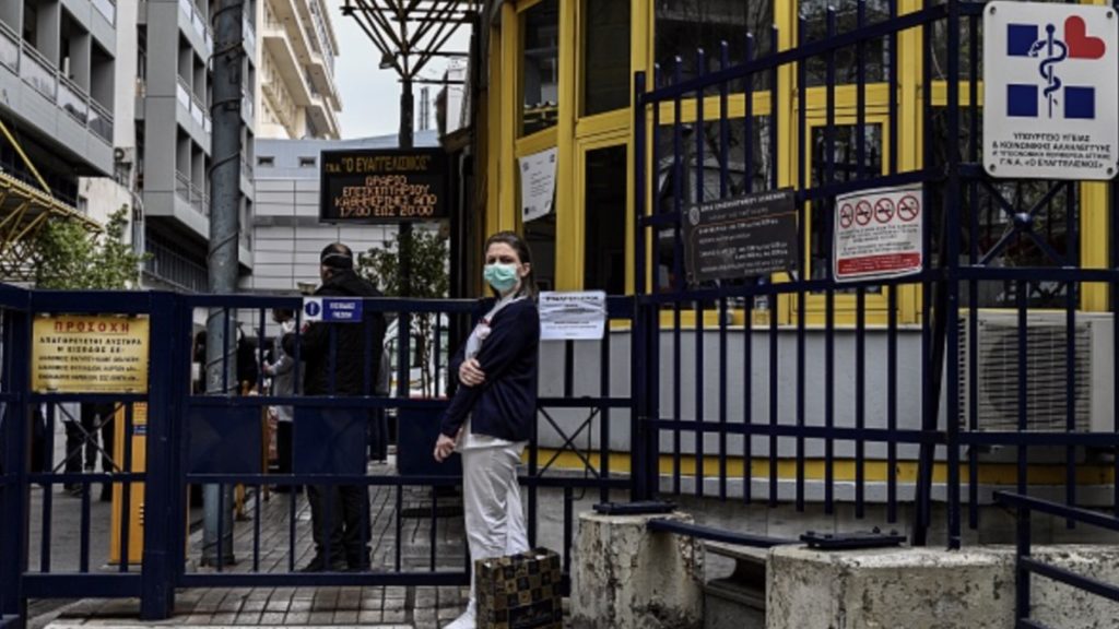 A member of the medical staff, wearing a facemask for protective measure, stands by the entrance of an hospital, in Athens, on April 1, 2020