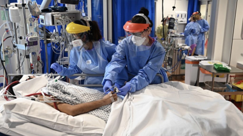 Members of the clinical staff wear personal protective equipment (PPE) as they care for a patient at the Intensive Care unit at Royal Papworth Hospital in Cambridge, on May 5, 2020.