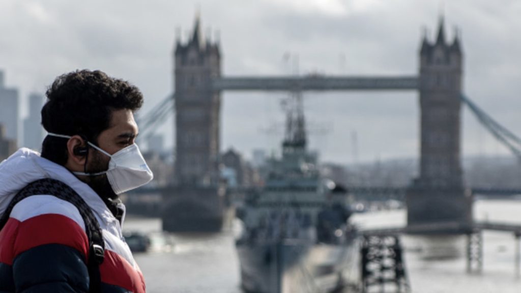 A man wearing a face mask walks over London Bridge, with Tower Bridge seen behind, as the outbreak of coronavirus intensifies on March 14, 2020 in London, England.