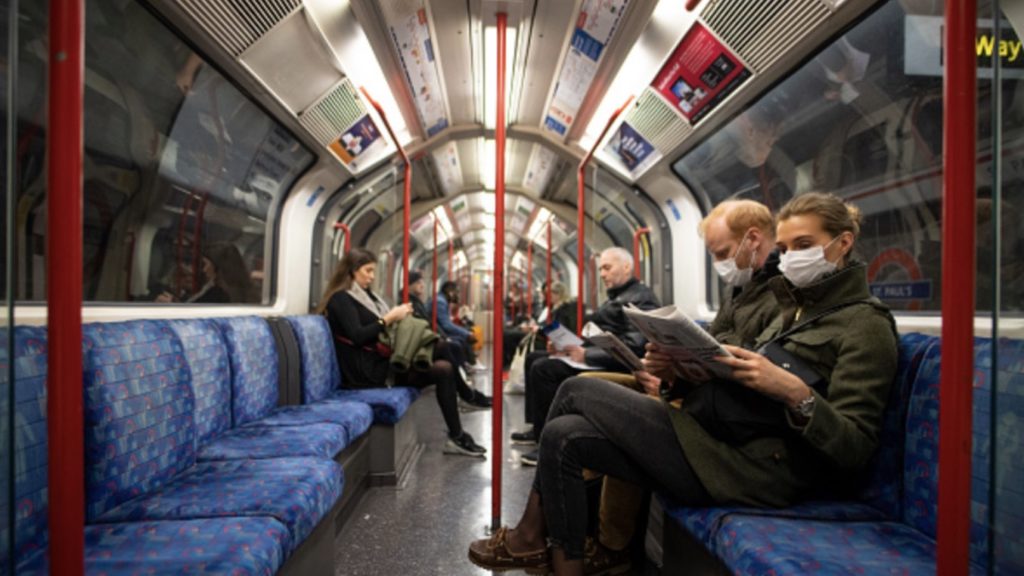 A couple sit on the Central Line Tube wearing protective face masks while reading a newspaper on March 19, 2020 in London, England