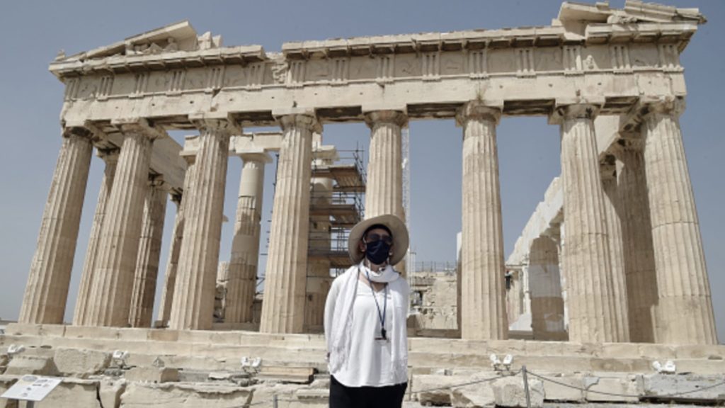 A Culture ministry employee wearing a face mask stands in front of the Parthenon temple as the Acropolis archaeological site opens to visitors on May 18, 2020 in Athens, Greece