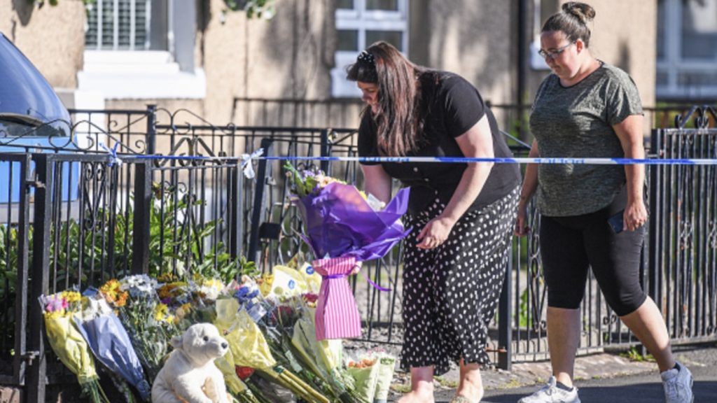 Members of the public lay flowers near the scene where three children have died in a house fire on June 20, 2020 in Paisley, Scotland.