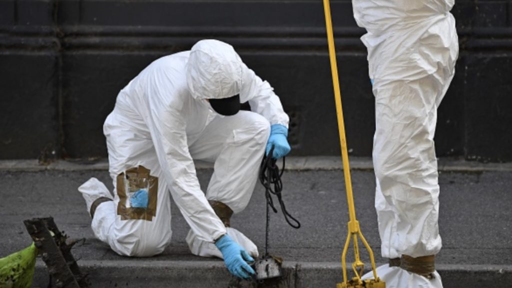Police forensics officers dressed in Tyvek protective PPE (personal protective equipment) suits and wearing masks, conduct a search of a drain near to Forbury Gardens park in Reading, west of London, on June 22, 2020, the scene of the June 20 stabbing spree.
