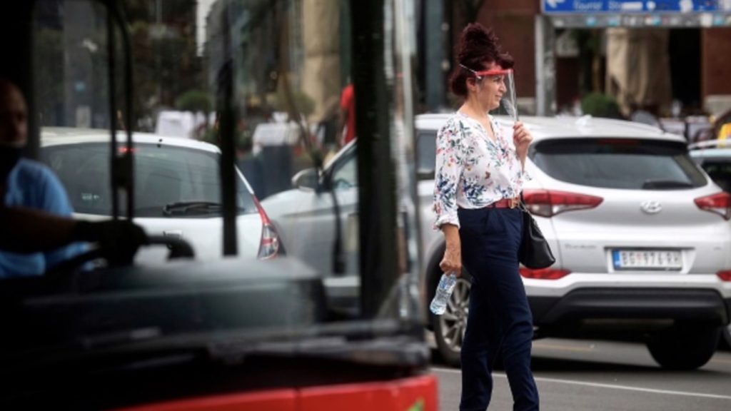 A woman wearing a protective face shield crosses a street in downtown Belgrade on July 3, 2020 during the spread of the novel coronavirus (COVID-19).